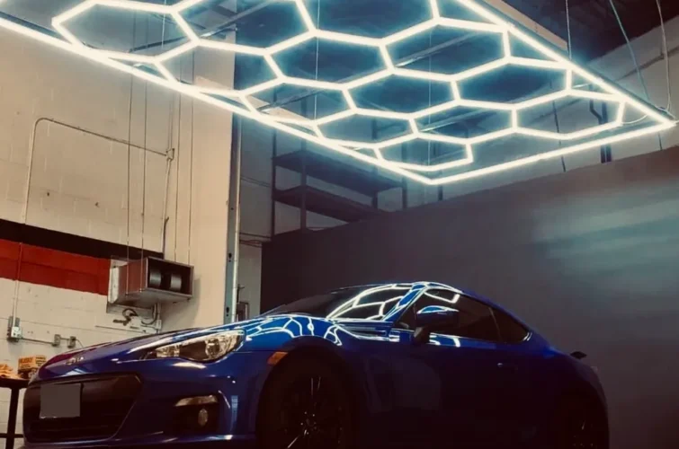 Blue sports car under modern hexagonal lighting in a car wash facility, showcasing expert detailing and quality service at Mr. Shine in Pickering.