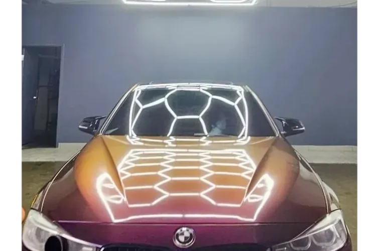 BMW car with a glossy finish reflecting overhead lighting in a clean, modern car wash setting, showcasing expert detailing and shine.